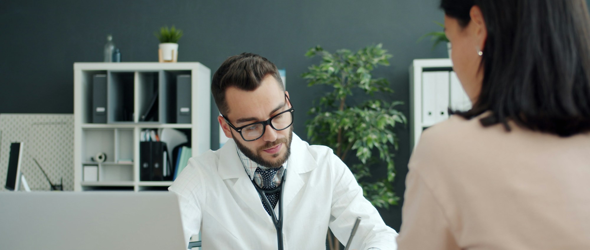 Physician taking notes while assessing a patient